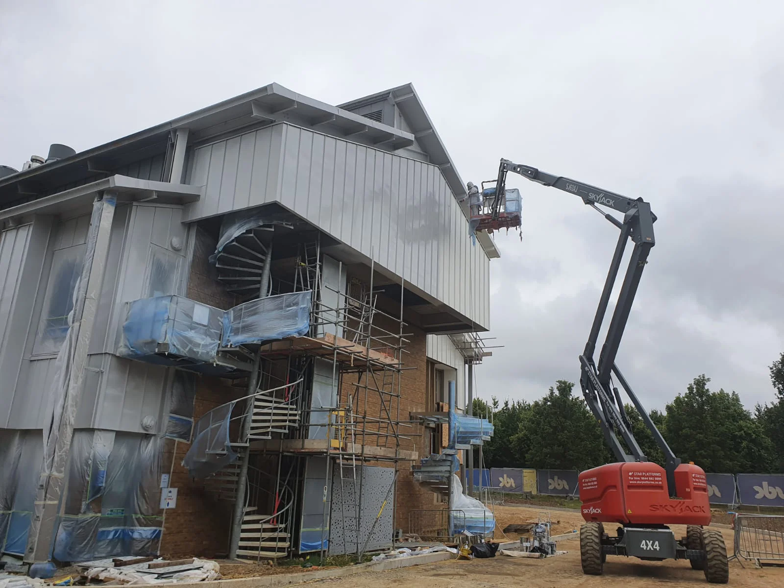 Vanda Coatings operative on cherry picker applying finish coat to cladding panels at Cambridge Science Park