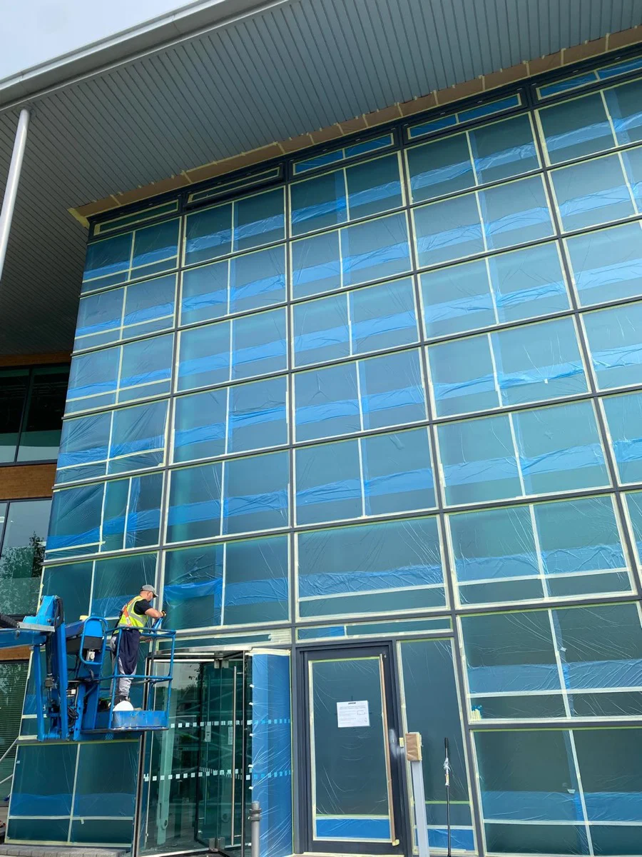 Vanda Coatings operative on MEWP platform spraying the entrance curtain wall at Central Park Manchester