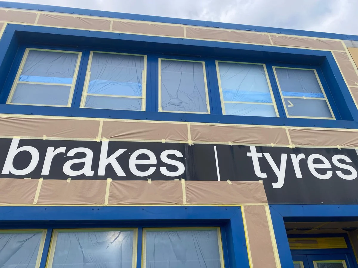 Halfords Autocentre Strood shop front during respraying works, glazing masked and blue frames visible