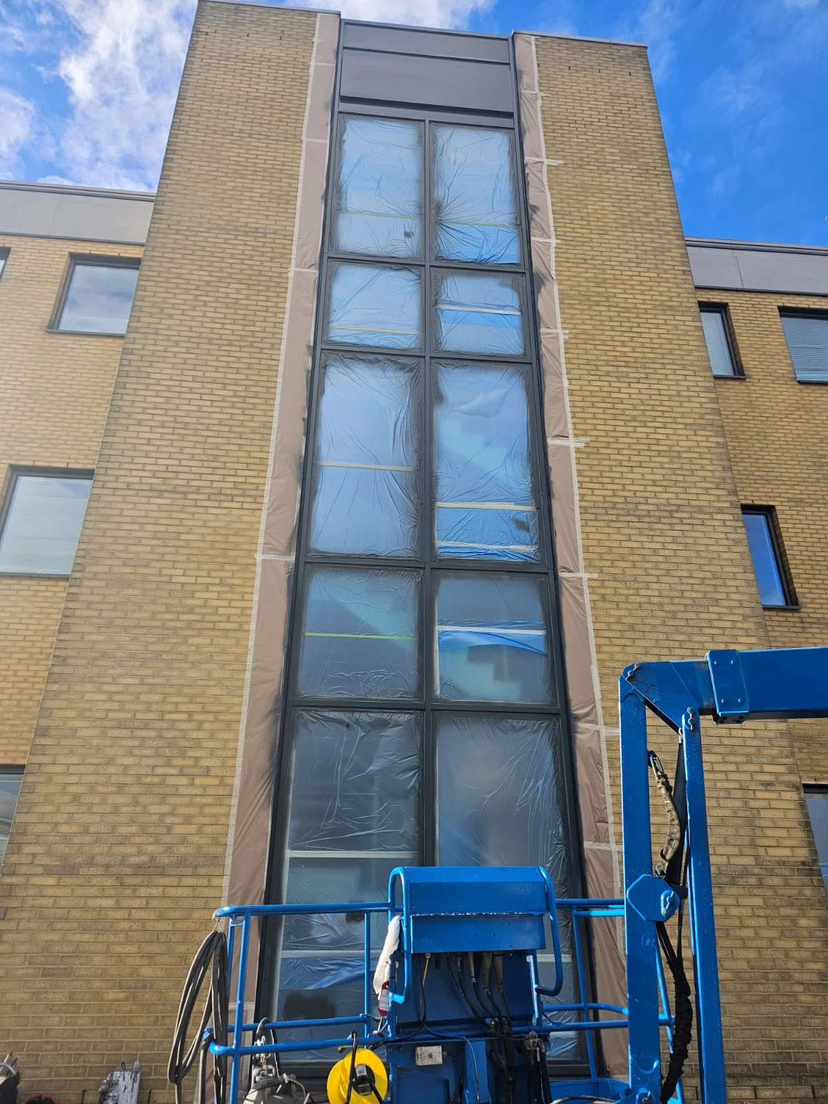 Vanda Coatings operative on cherry picker masking curtain wall glazing at Jubilee House, Oxford