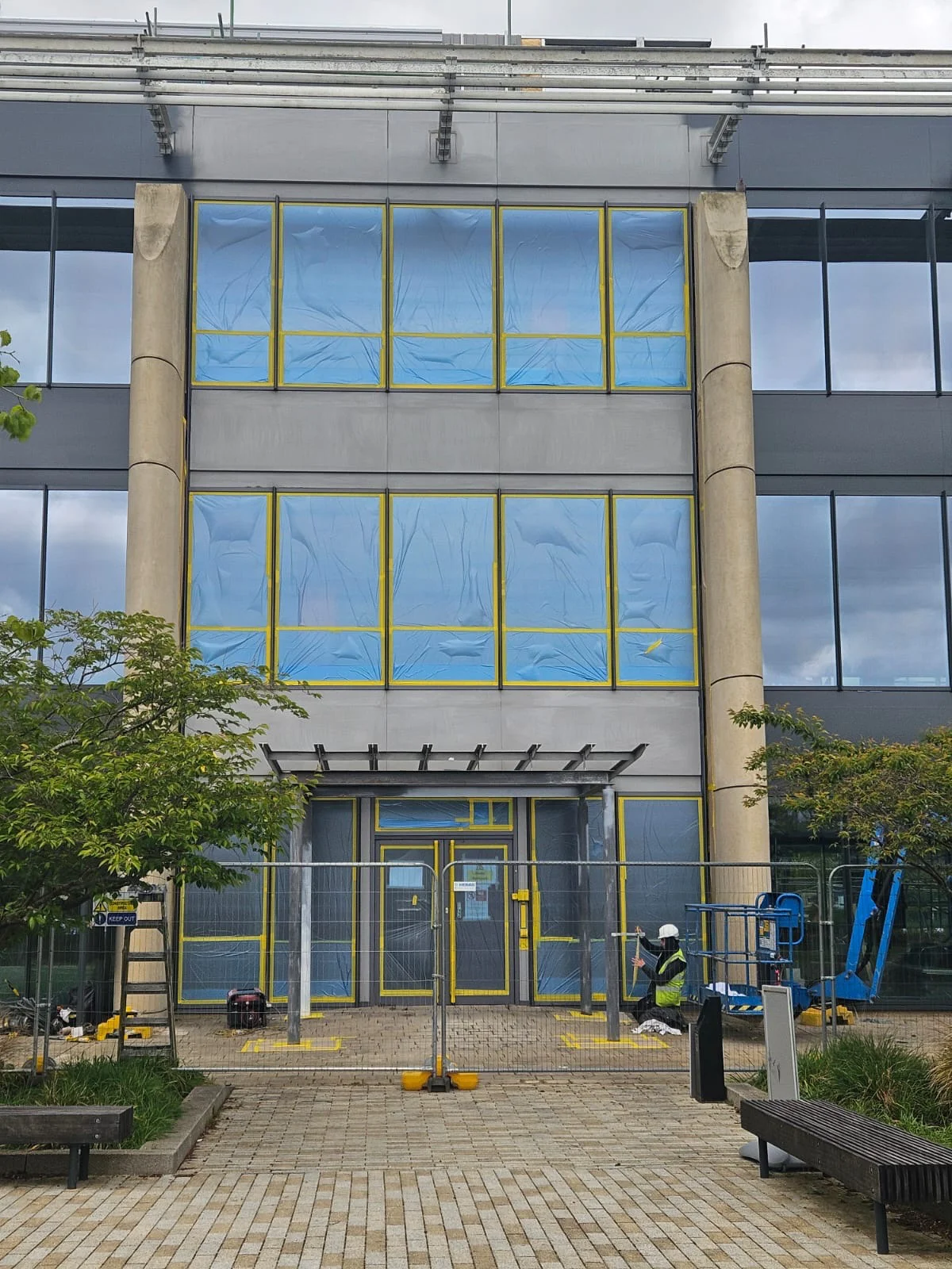 Curtain wall sections masked with protective sheeting prior to respraying at Jubilee House, Oxford