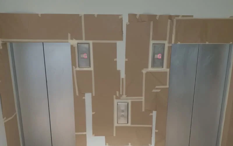 Lift door lobbies masked and prepared for electrostatic spray recoating by Vanda Coatings