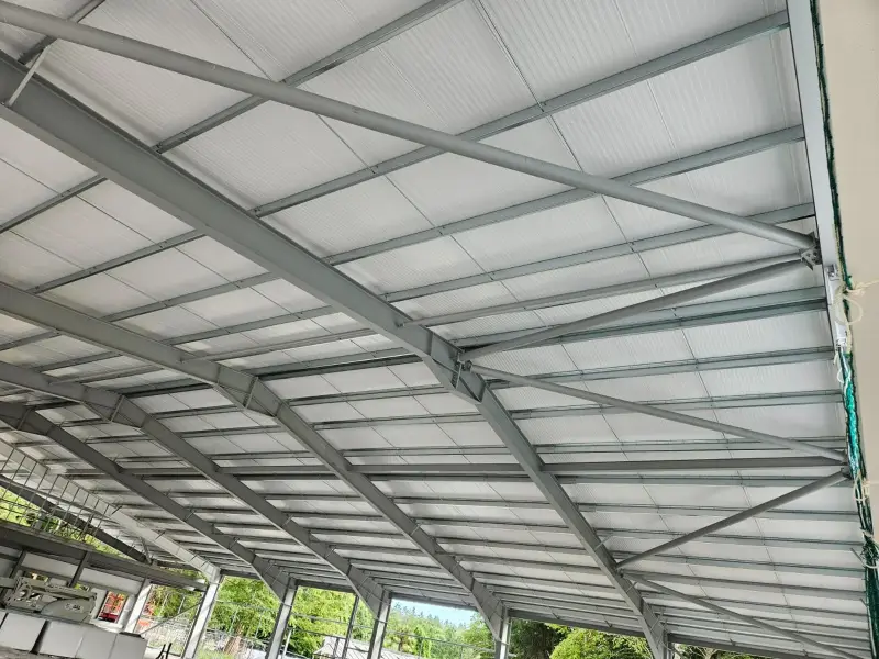 Industrial steel purlins and ceiling structure before spray painting, showing unpainted grey metalwork