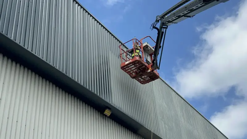 Vanda Coatings operative on a cherry picker spraying cladding on a large commercial building