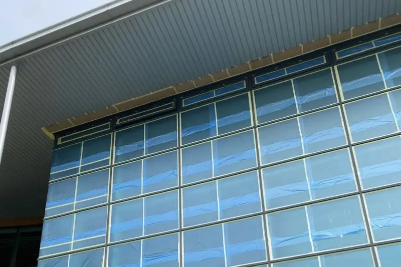 Vanda Coatings operative on a cherry picker masking a large curtain wall facade on an occupied commercial building