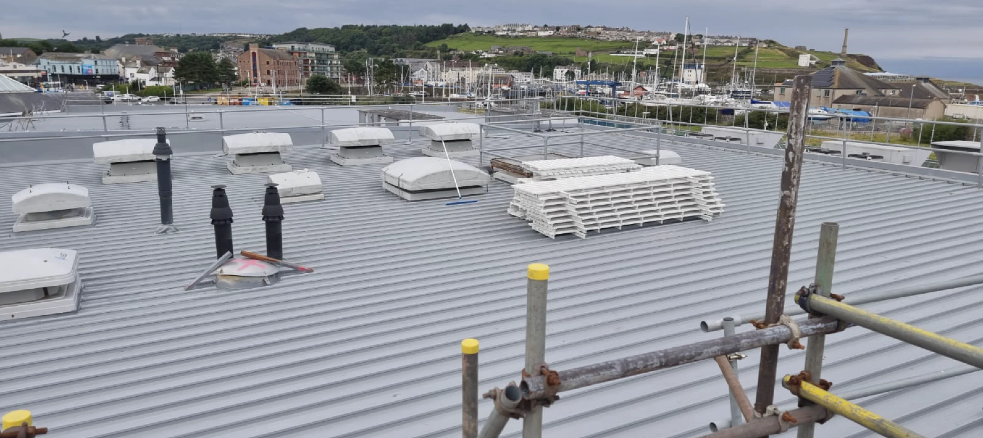 Recoated industrial roof with scaffolding and harbour view, Whitehaven, by Vanda Coatings